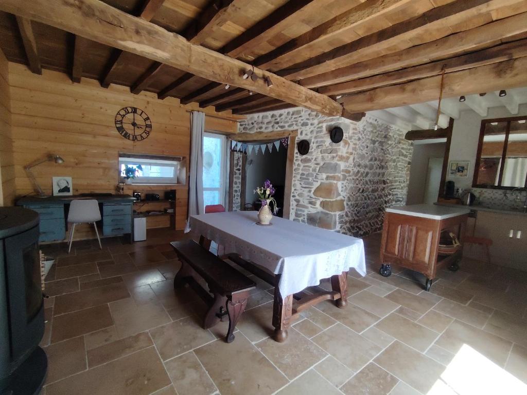 a dining room with a table and a stone wall at Les pierres qui parlent in Précilhon