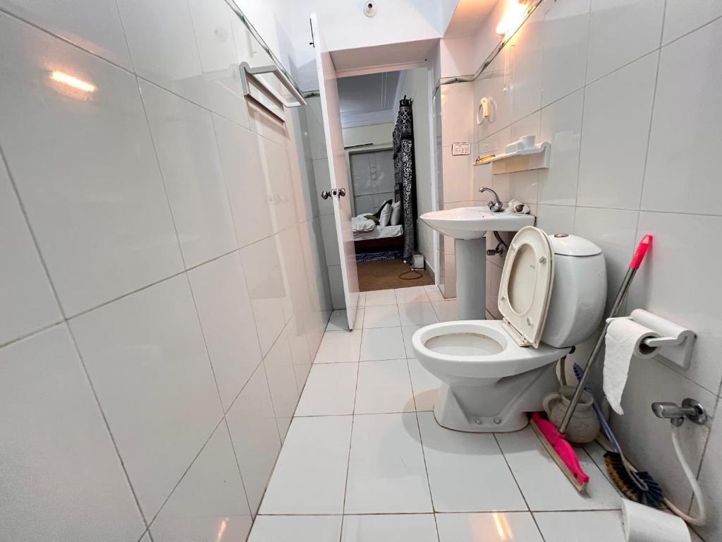 a white bathroom with a toilet and a sink at Diwan longues in Murree