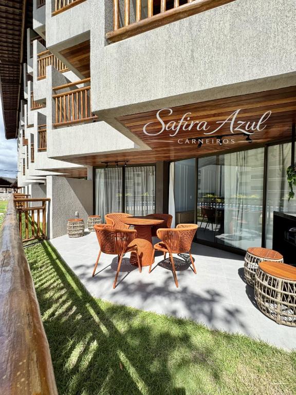 a patio with a table and chairs in front of a building at Safira Azul Luxury Flat Carneiros in Tamandaré