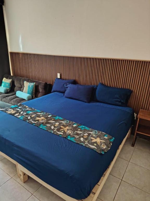 a large blue bed with blue pillows and a couch at Casa las Flores in Puerto Vallarta