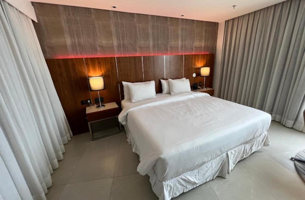 a bedroom with a large white bed and two lamps at Suíte Luxo Mar em Hotel Nacional in Rio de Janeiro