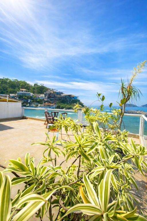 a patio with a view of the water and a bench at Suites Quebra Mar in Rio de Janeiro