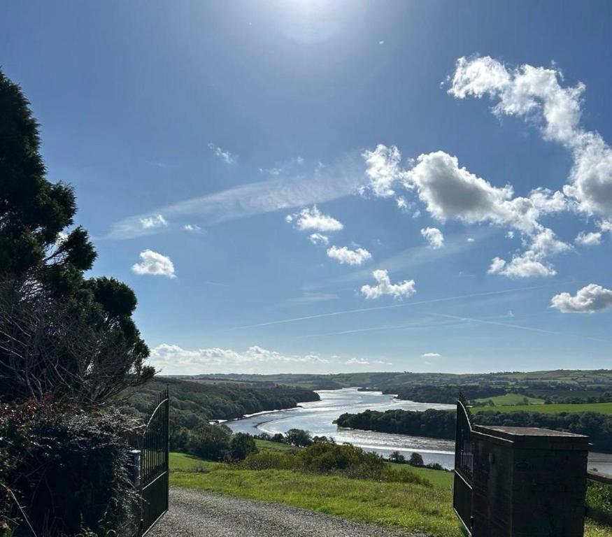 a view of a river from a hill with a gate at The Waterfront House in Kinsale, hosted by Exquisite Holiday Homes in Dunderrow