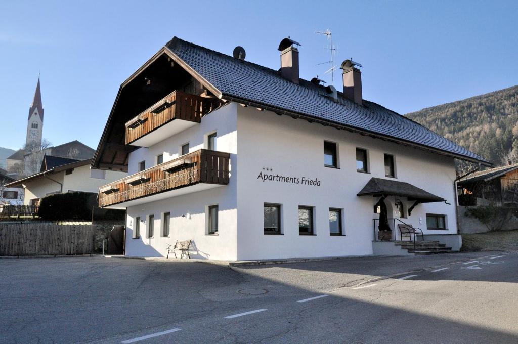 a white building with a black roof at Apartments Frieda in Valdaora