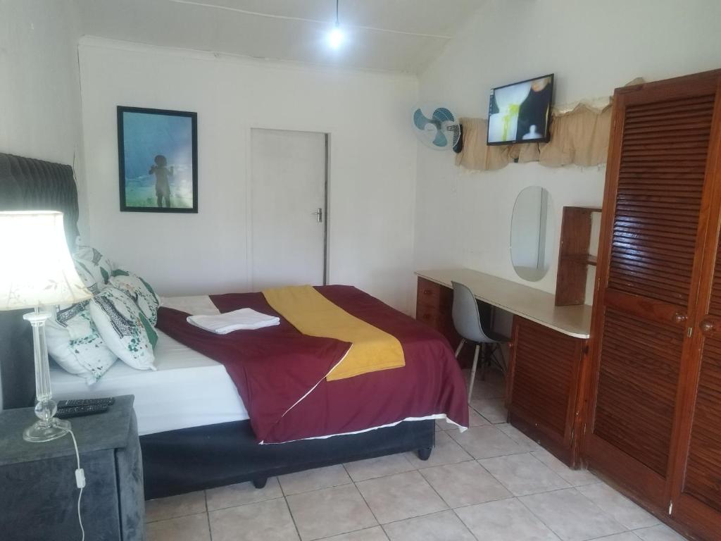 a bedroom with a bed and a desk in it at J&J Paradise Guesthouse in Pietermaritzburg