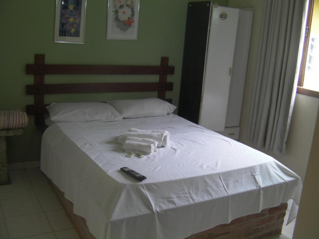 a bed with two towels and a remote control on it at Pousada Dom Diego in Jacaraípe