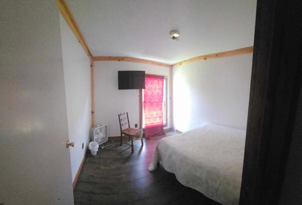 a bedroom with a bed and a chair and a window at Leapin leanas in Monson