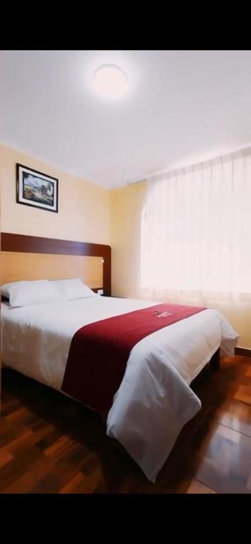 a bedroom with a large bed with white and red sheets at Kaypi Yireh in Cabanaconde