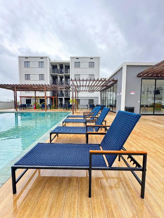 a row of blue lounge chairs in a swimming pool at apartamento ana julia modesto in Juazeiro do Norte
