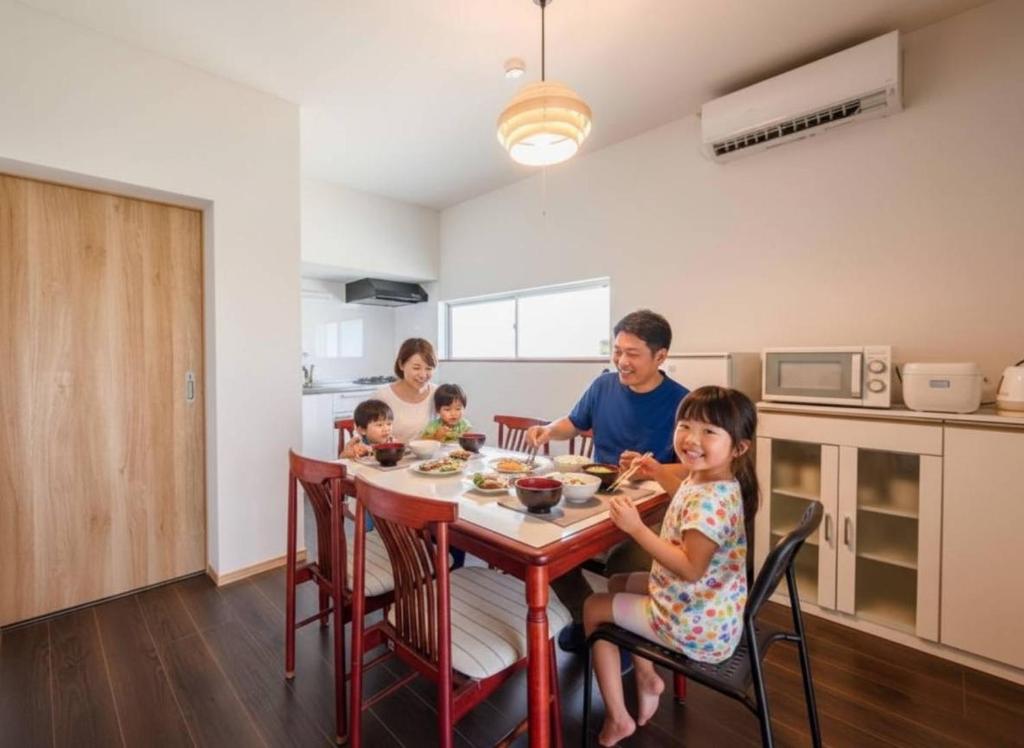 a family eating food at a table in a kitchen at Kizuna House Yuzuriha in Minamiawaji