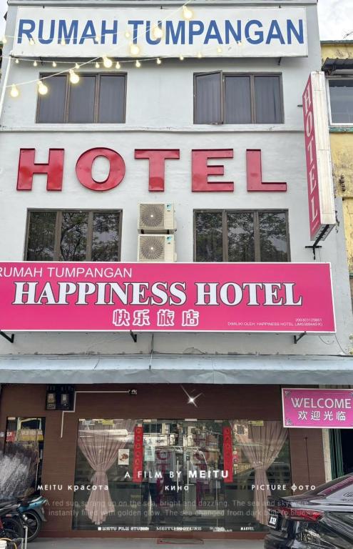 a building with a sign for a hotel at Happiness Hotel in Kulai