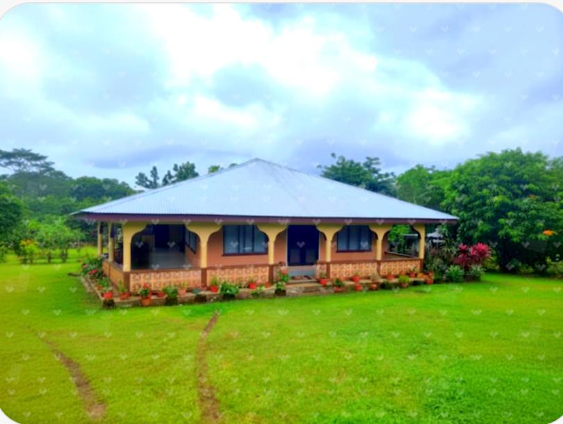 a house with a large yard with a green field at Dream Big Accommodation in Apia