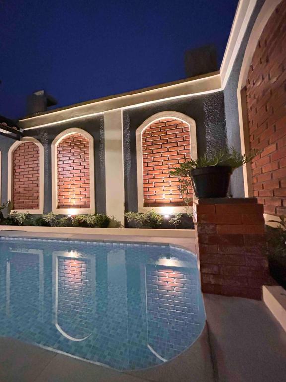 a swimming pool in front of a house at night at Sabi House Lesmana in Timuran