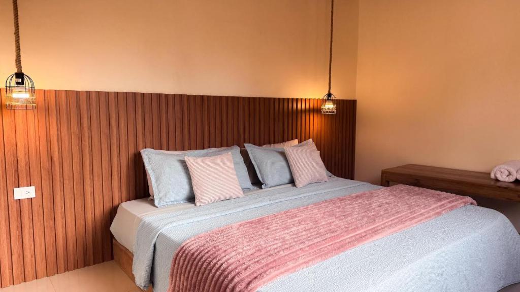 a bedroom with a large bed with pink and white pillows at Villa Monarca in Ayampe