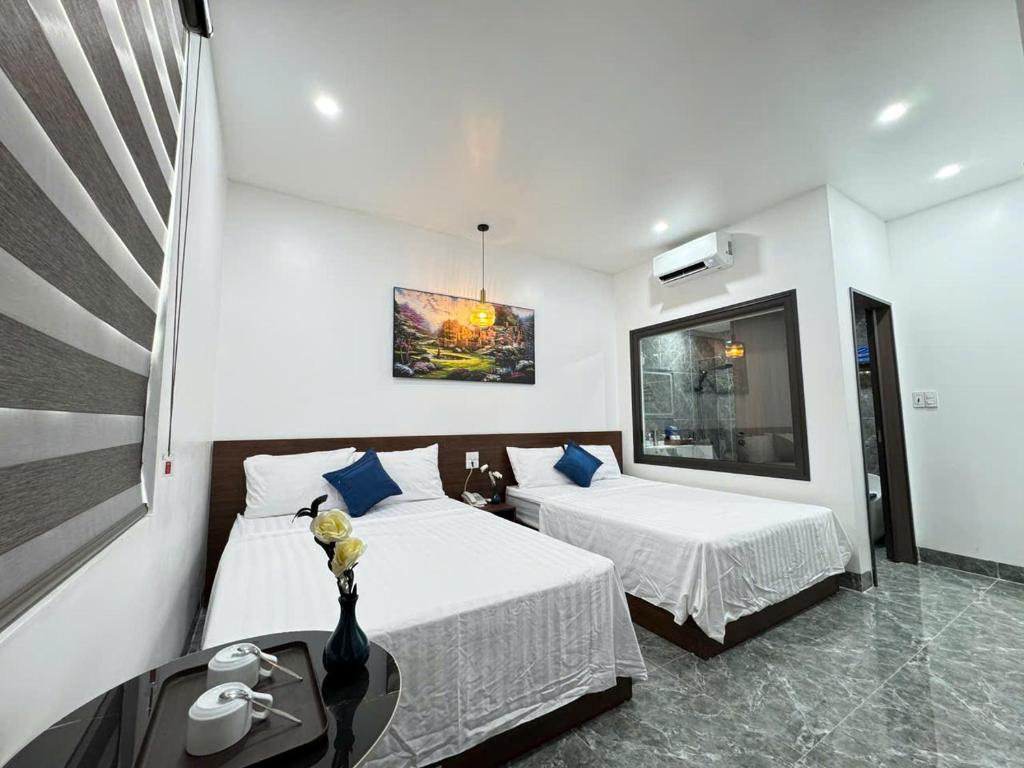 a hotel room with two beds and a table at Khách Sạn MoonKnight 2 in Sầm Sơn