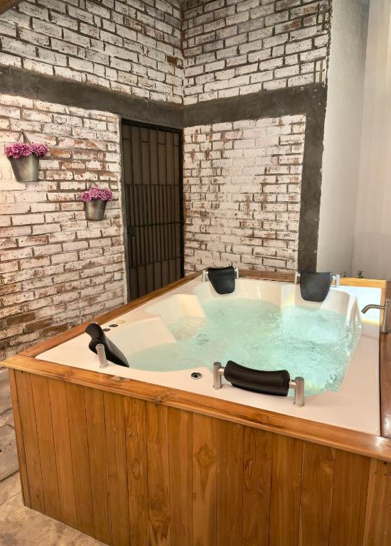 a jacuzzi tub in a room with a brick wall at El marqués casa boutique in Ríohacha