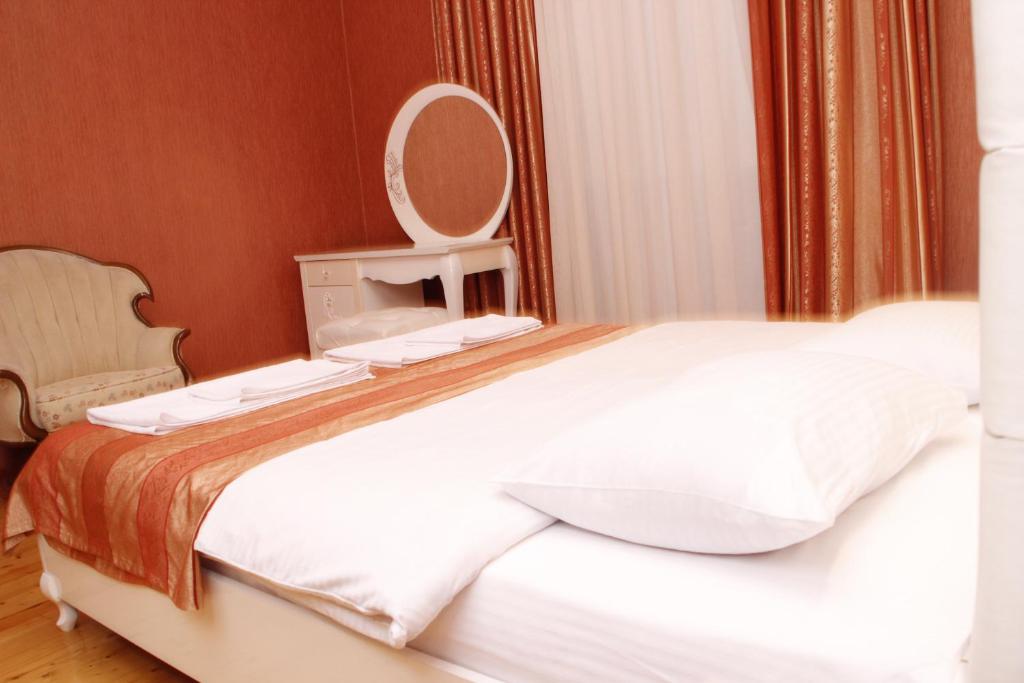 1 dormitorio con 1 cama blanca grande y espejo en Baku Butik Mini-Hotel, en Baku