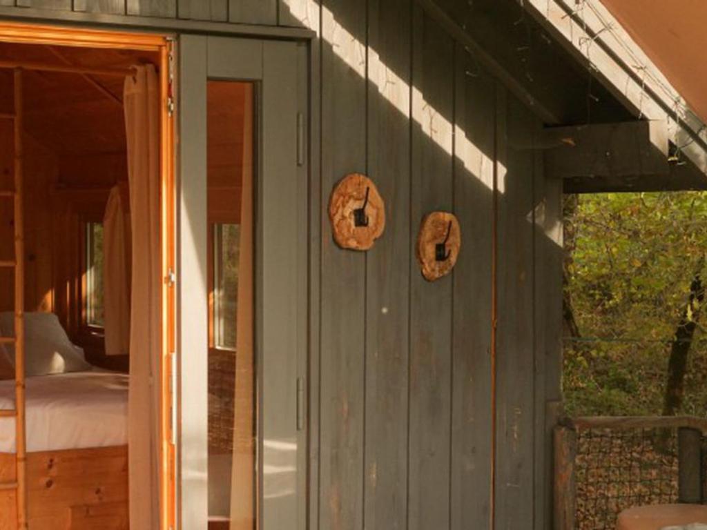 a green house with two wreaths on the wall at Cabane cosy pour 2 avec jacuzzi - API-1-52-2485 in Saint-Amand-de-Coly