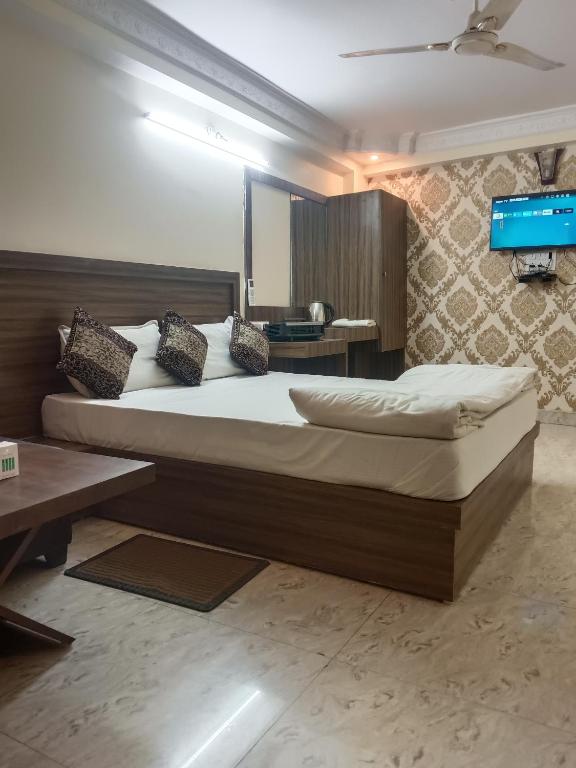 a bedroom with a large bed and a tv at Hotel Atithi Palace in Jabalpur