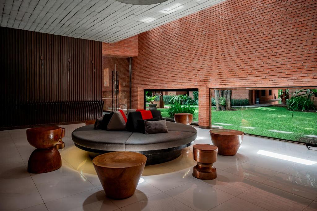 A brick-lined lounge centers on a large circular sofa facing a planted garden.