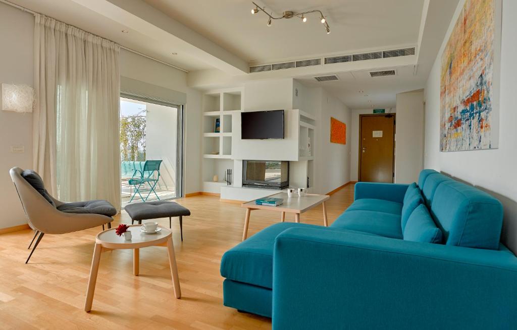 een woonkamer met een blauwe bank en een tafel bij Scale Suites in Athene