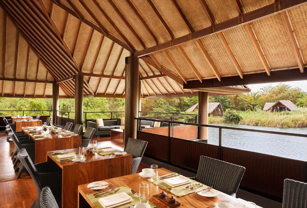 a restaurant with tables and chairs and a view of the water at Jetwing Vil Uyana, A Luxury Reserve in Sigiriya