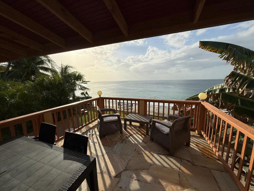 a balcony with chairs and a table and the ocean at Birdies Nest Upper 2 Bedroom Beach View in Black Rock