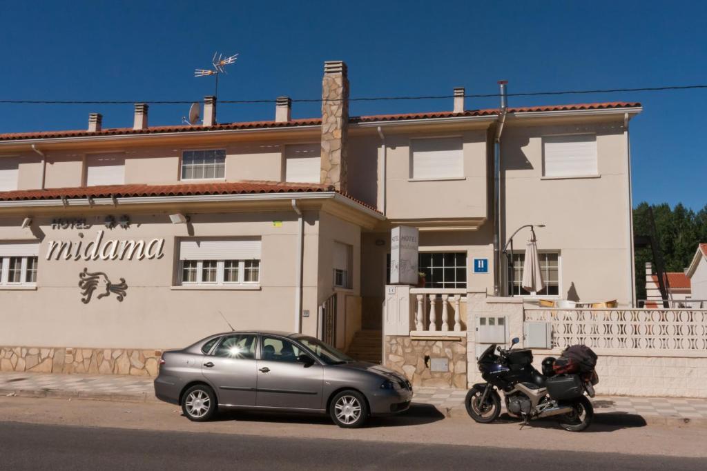 a car and a motorcycle parked in front of a house at Midama in Chillarón de Cuenca