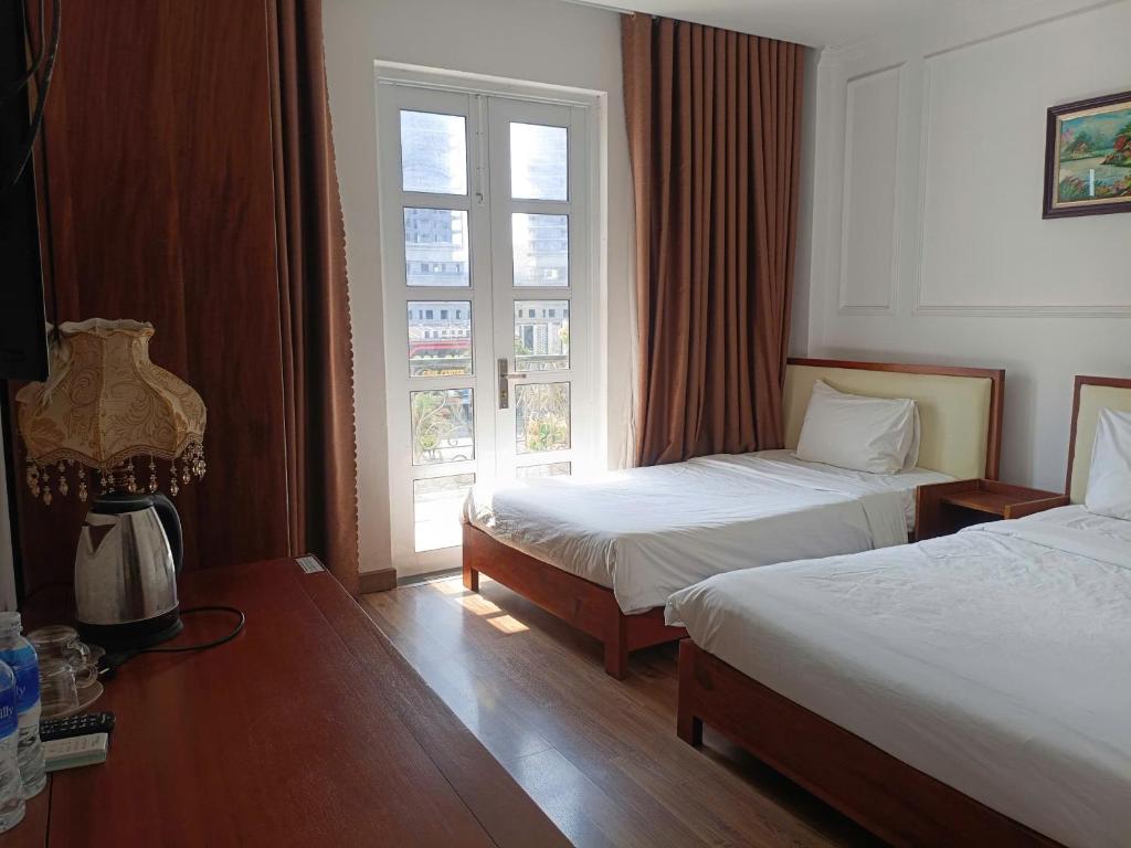 a hotel room with two beds and a window at Queen-Hotel in Quy Nhon