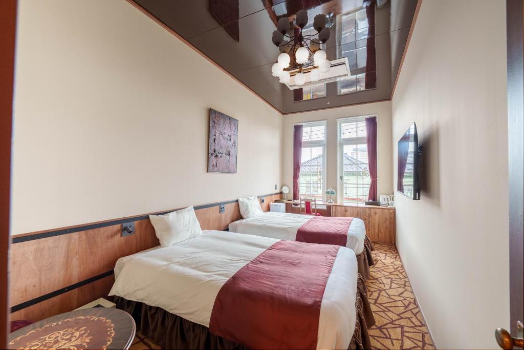 two beds in a room with two windows at T9 Hakodate in Hakodate