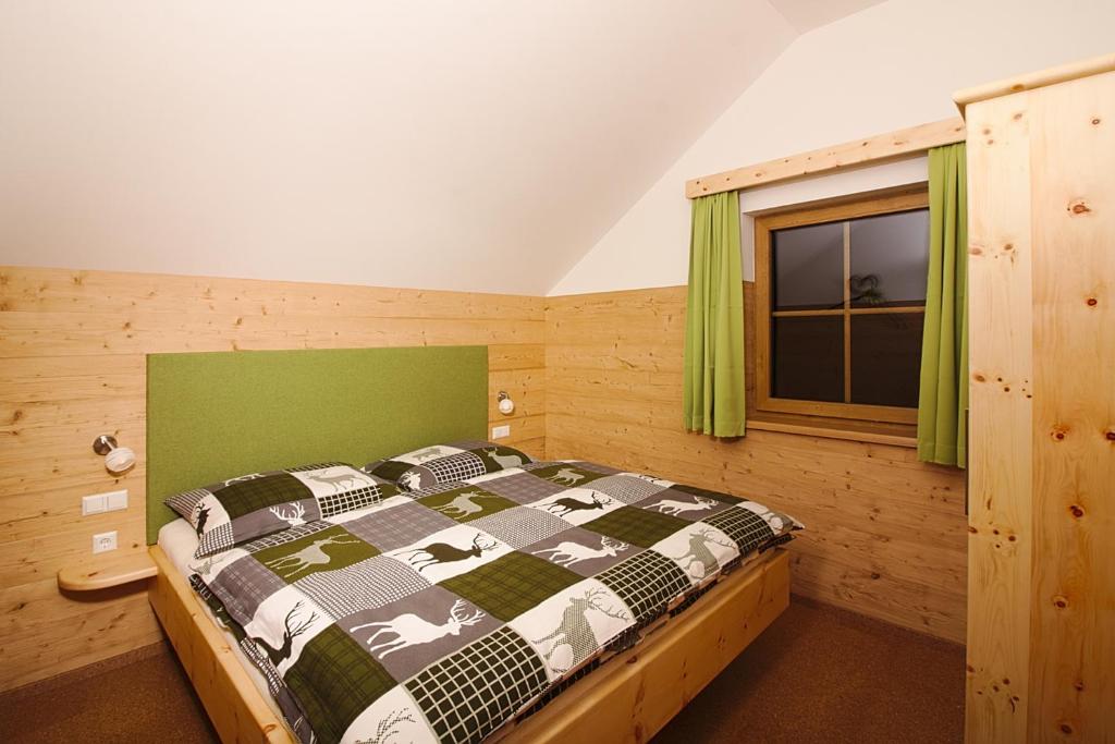 Schlafzimmer mit einem Bett und einem Fenster mit grünen Vorhängen in der Unterkunft Bio Chalet "Sonne" in Weisspriach