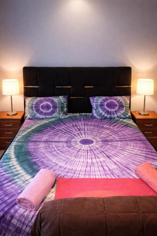 a bedroom with a large purple bed with two lamps at Cutting Edge Guest House in Daranka