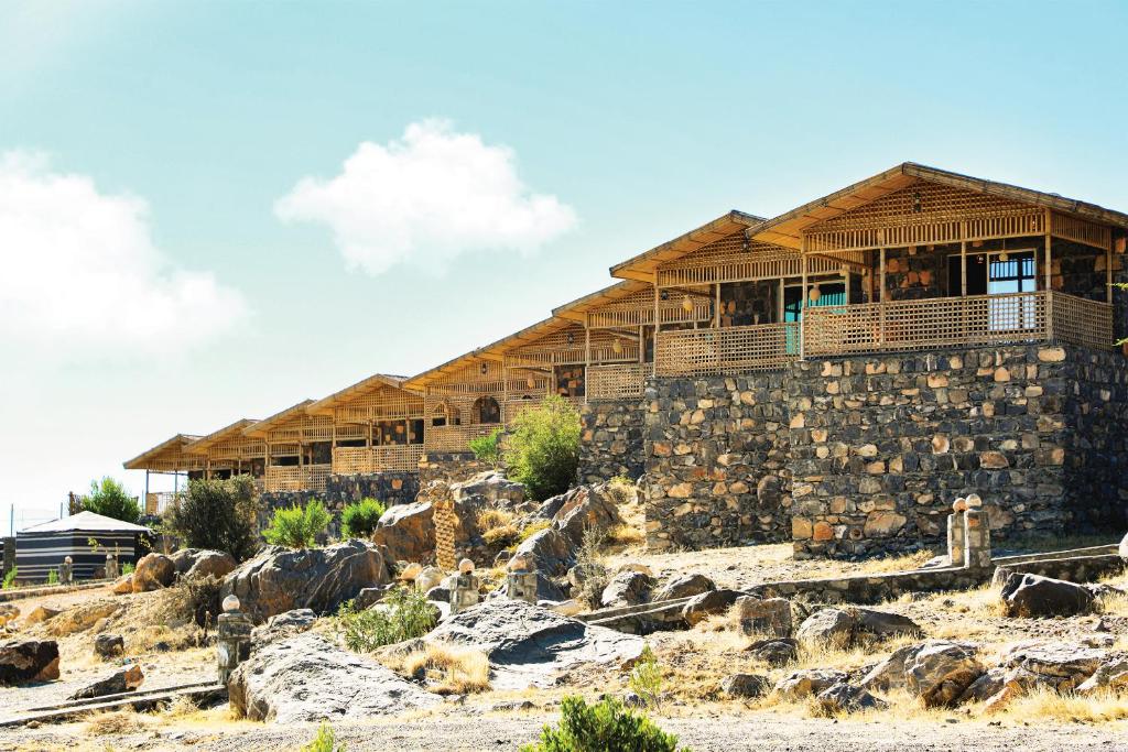 a building on top of a hill with rocks at Sama Jabal Shams Resort in Dār Sawdāʼ