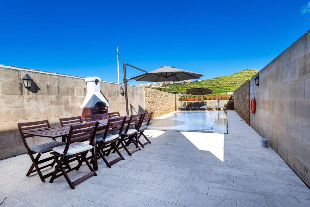a patio with a table and chairs and an umbrella at Solaris Holiday Home in Għasri