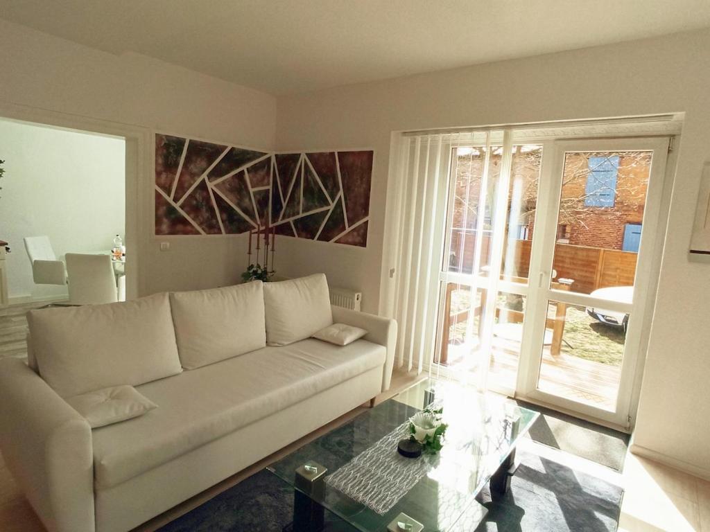 a living room with a white couch and a glass table at Familienfreundliche Fewo mit Garten in Schwarz