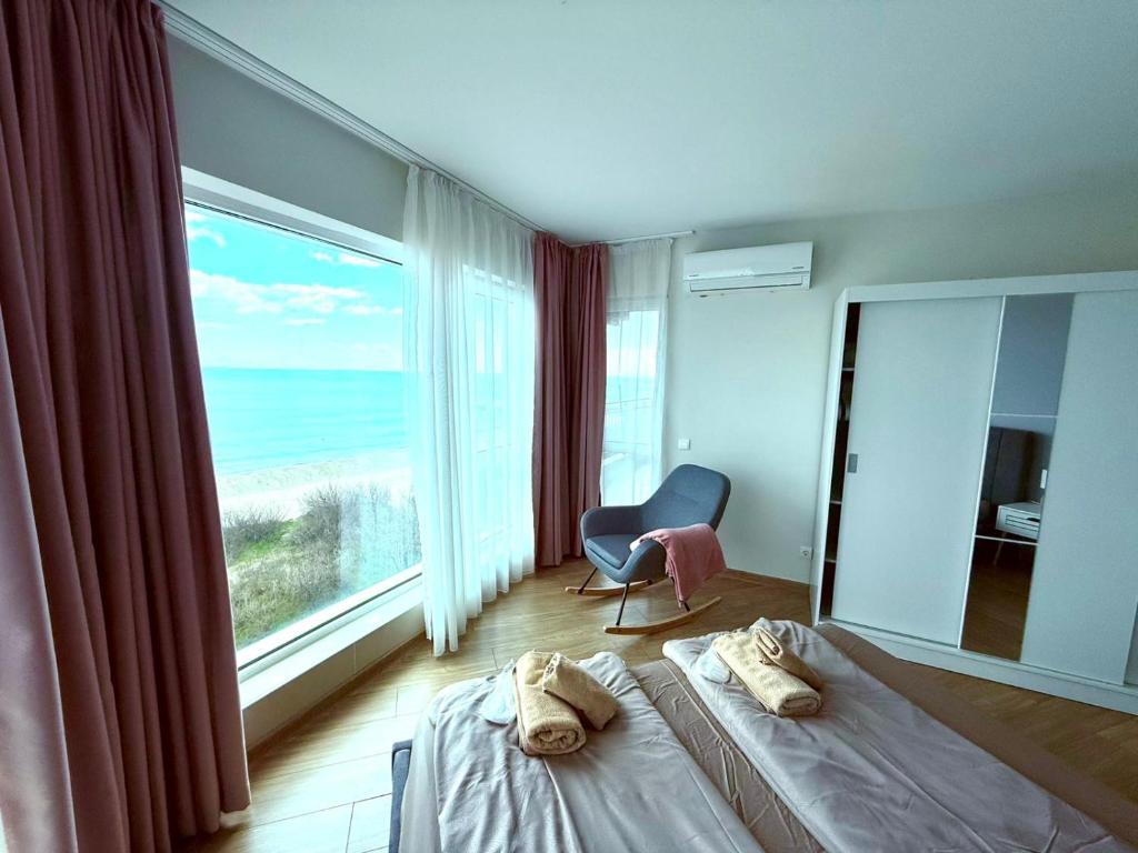 a bedroom with a bed and a chair and a large window at Apartment Sunrise Pomorie in Pomorie