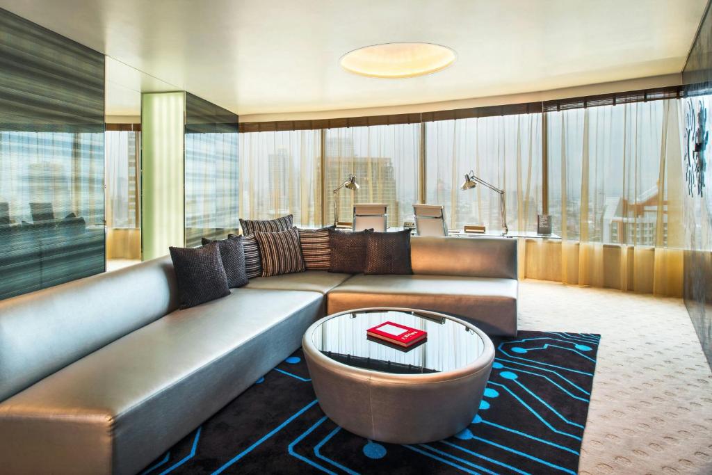 A lounge and work area with a curved sofa, two desk lamps, and expansive windows.