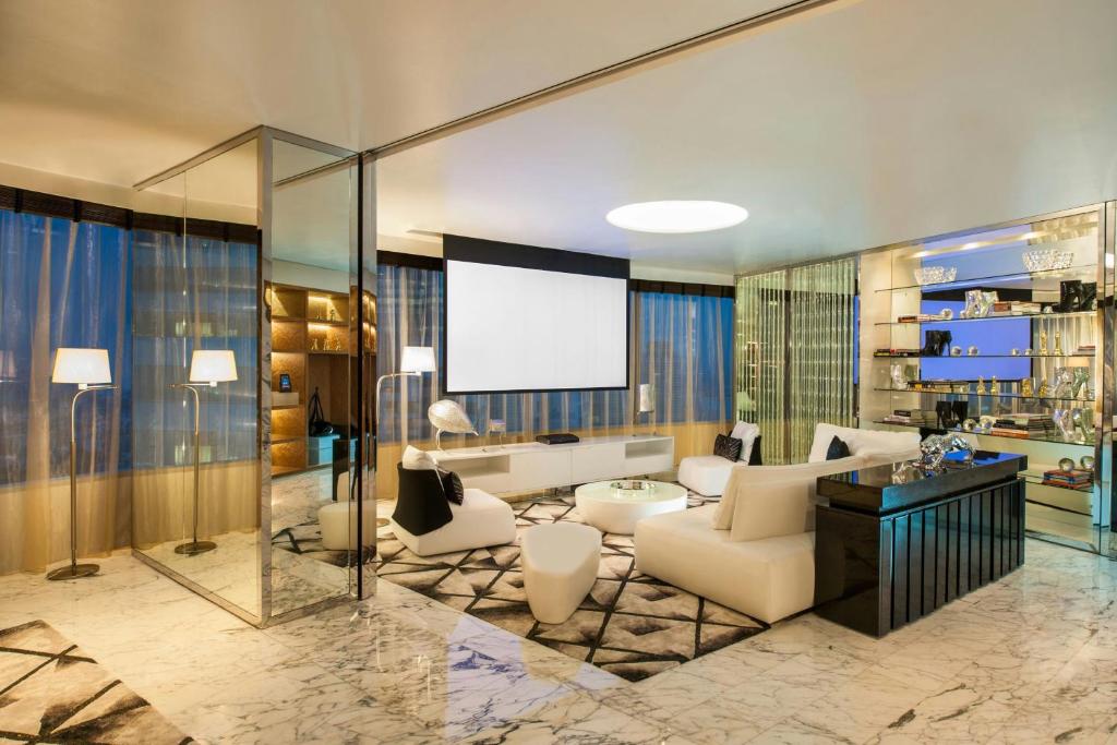 A glass-enclosed lounge with sofas, a projection screen and a compact bar.