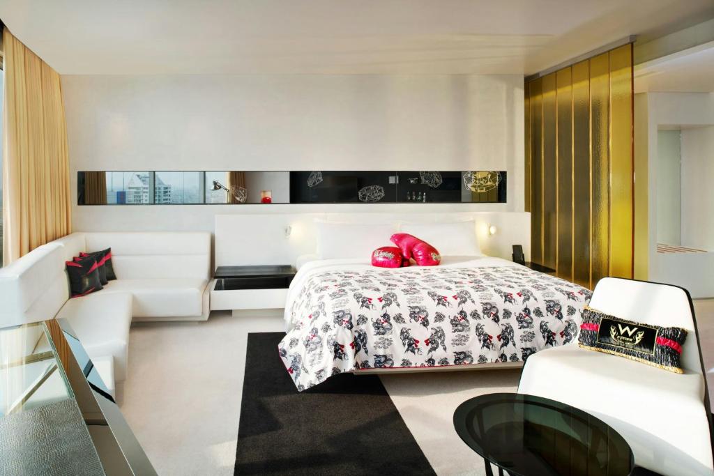 A spacious king room with a sofa, statement gold partition and separate lounge chair.