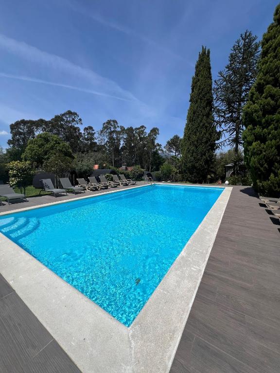 a swimming pool in a villa with chairs and trees at Hotel Rural Solar das Arcadas in Ponte de Lima