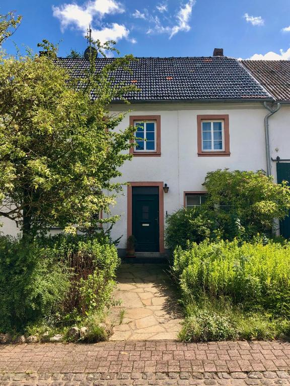 a white house with a red door at NAO Eifelhaus von 1875 mit Garten in Üxheim