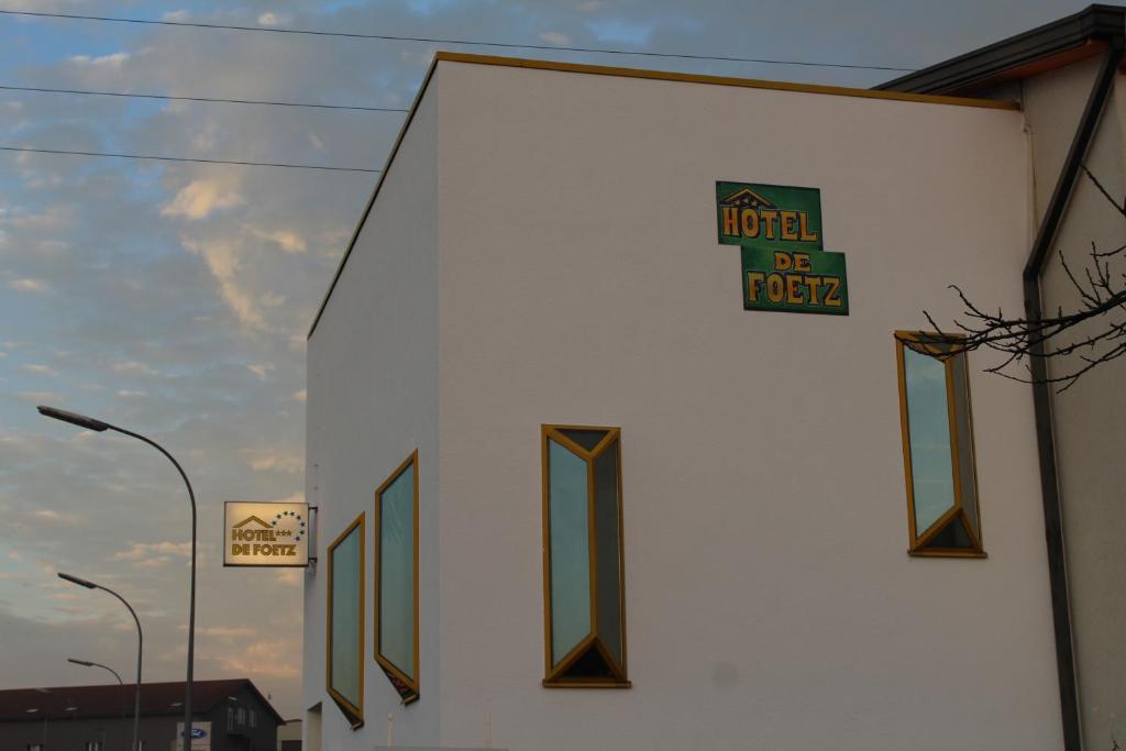 a white building with a sign on the side of it at Hotel de Foetz in Foetz