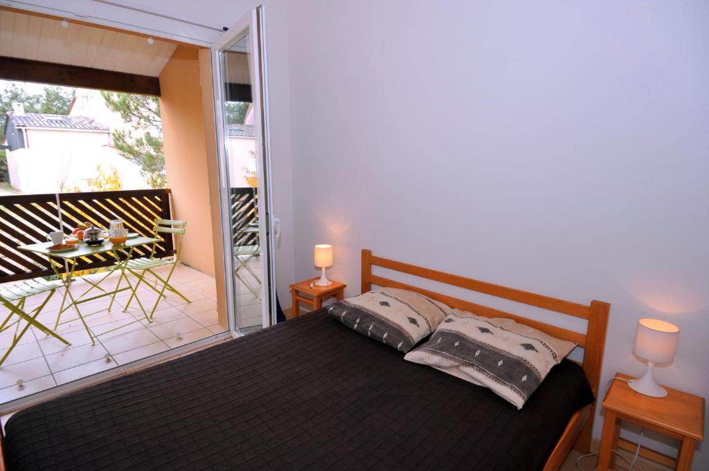 a bedroom with a bed and a balcony with a table at Lagrange Vacances - Les Hameaux de l'Océan in Carcans