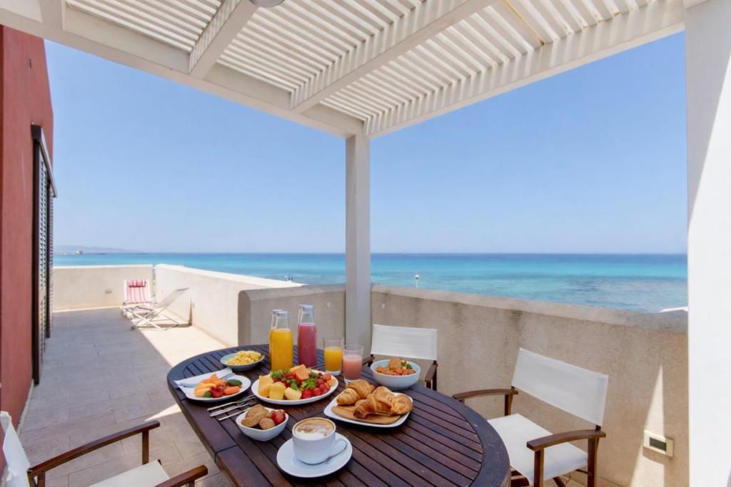 a table with food on a balcony with the beach at Terrazza Sul Mare in Trapani