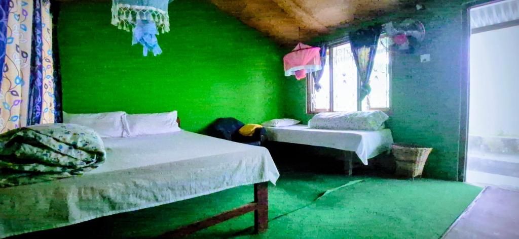 a green room with two beds and a window at Riverside guest house in Besisahar