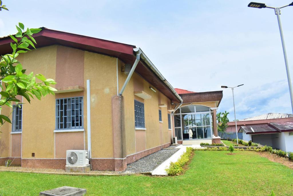 a yellow house with a grass yard in front of it at Villa les 3 oisillons in Kribi