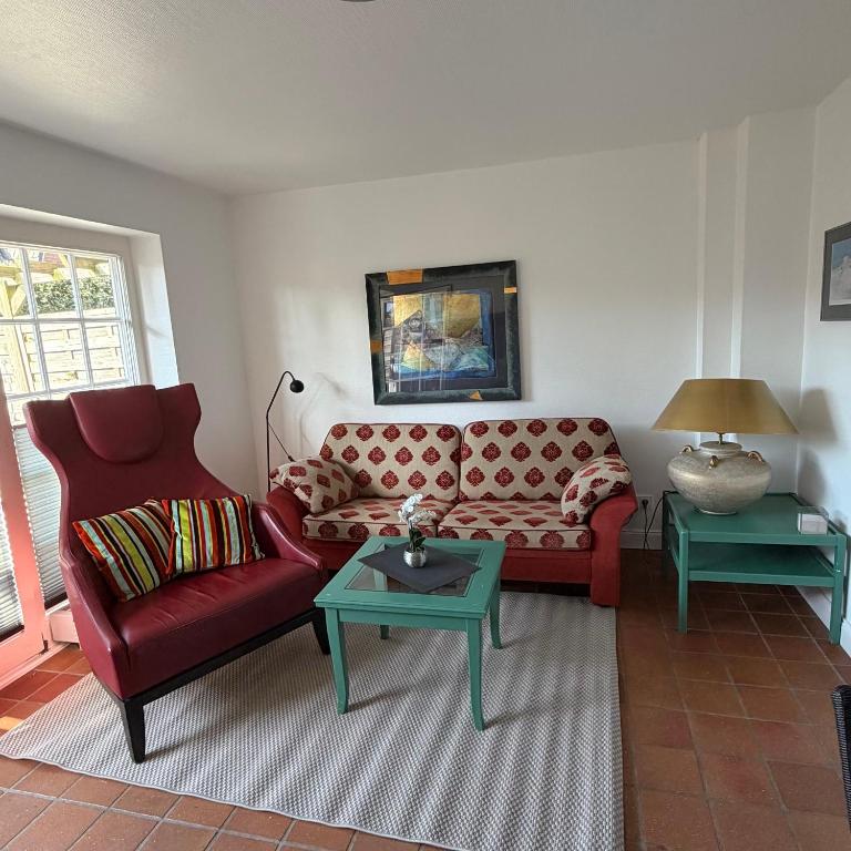 a living room with a red couch and two tables at Kastanienhüs Apartment in Westerland