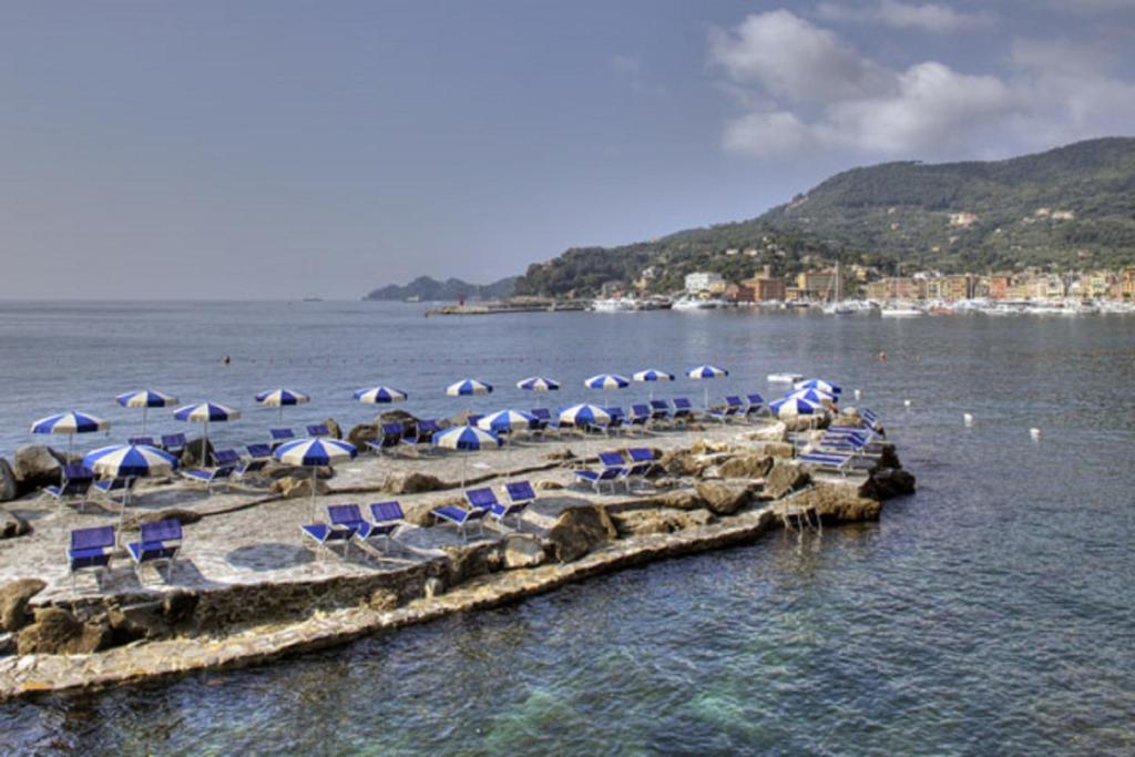 a beach with chairs and umbrellas on the water at Hotel Continental in Santa Margherita Ligure