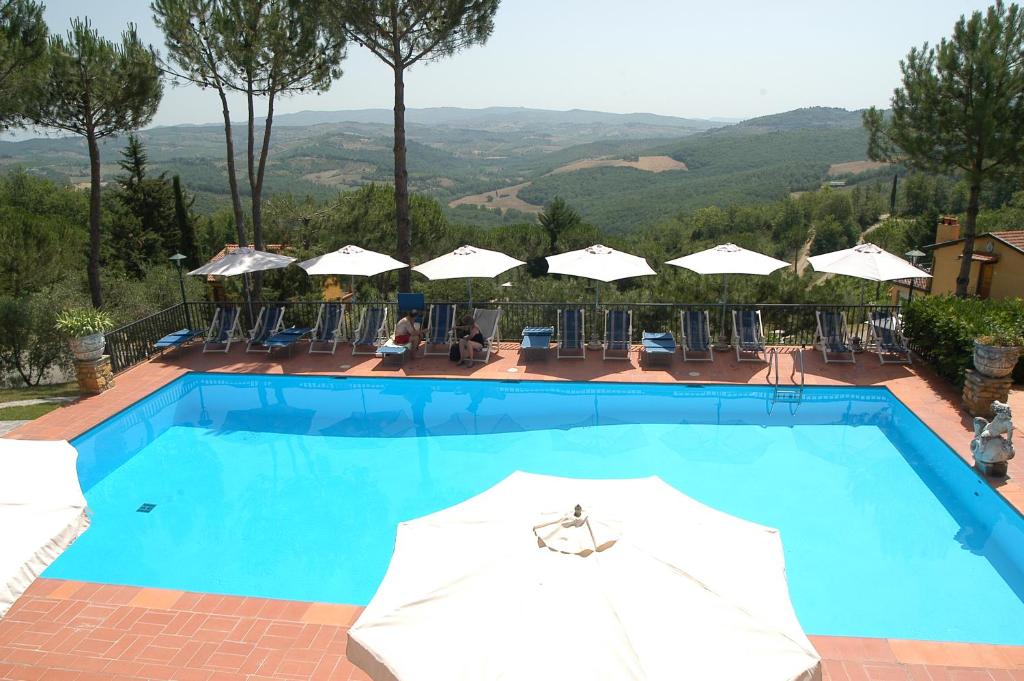 uma grande piscina azul com guarda-sóis e cadeiras em Poggio d'Oro em San Donato in Poggio