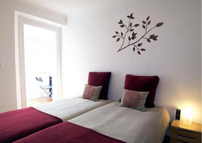 a bedroom with a bed with a tree on the wall at Estrela Cozy Apartment in Lisbon